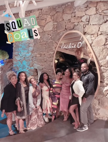 A group of people smiling and posing for a photo in front of a large mirror