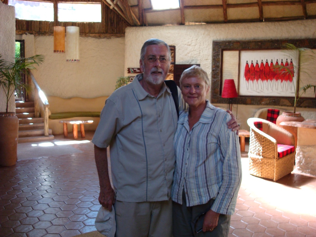An older couple stands together in a warmly lit room