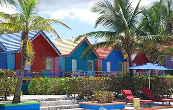 Colorful beach huts surrounded by umbrellas and palm trees