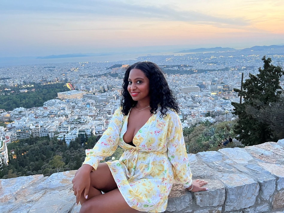 A woman in a yellow dress sits on a ledge