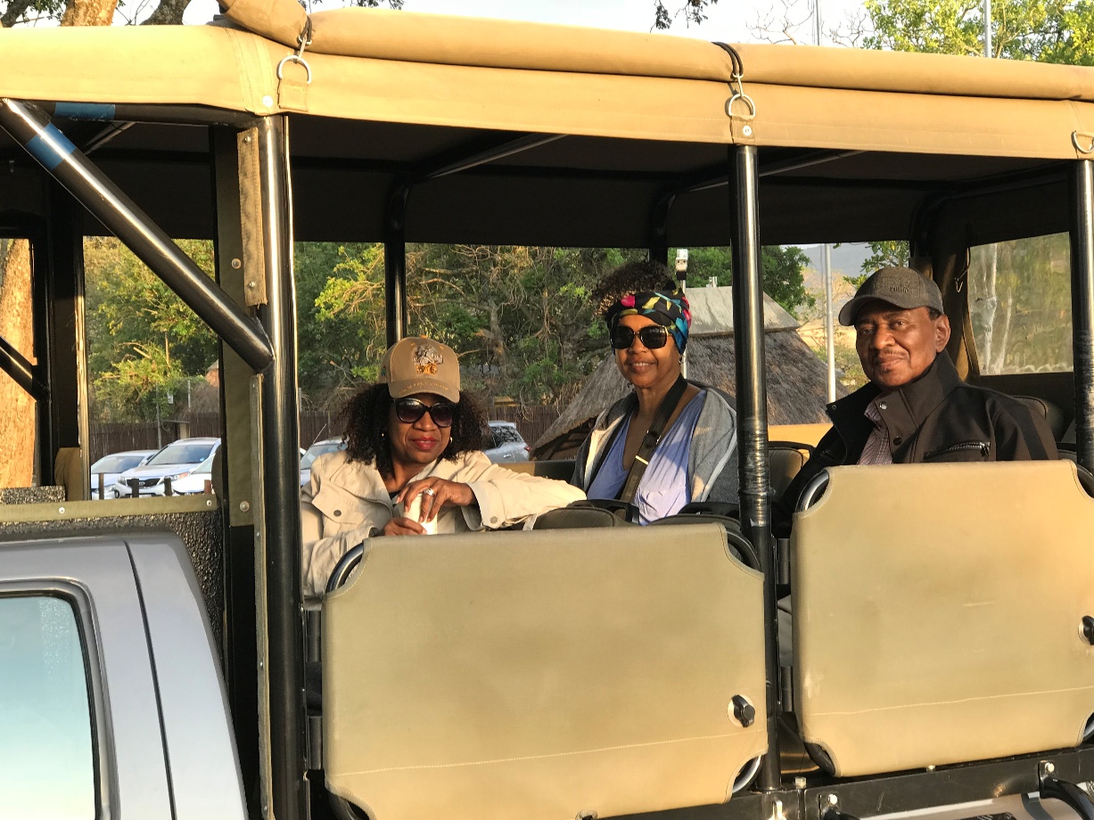 Three people seated in the back of a safari vehicle