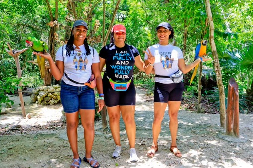 Three women in casual attire hold colorful parrots