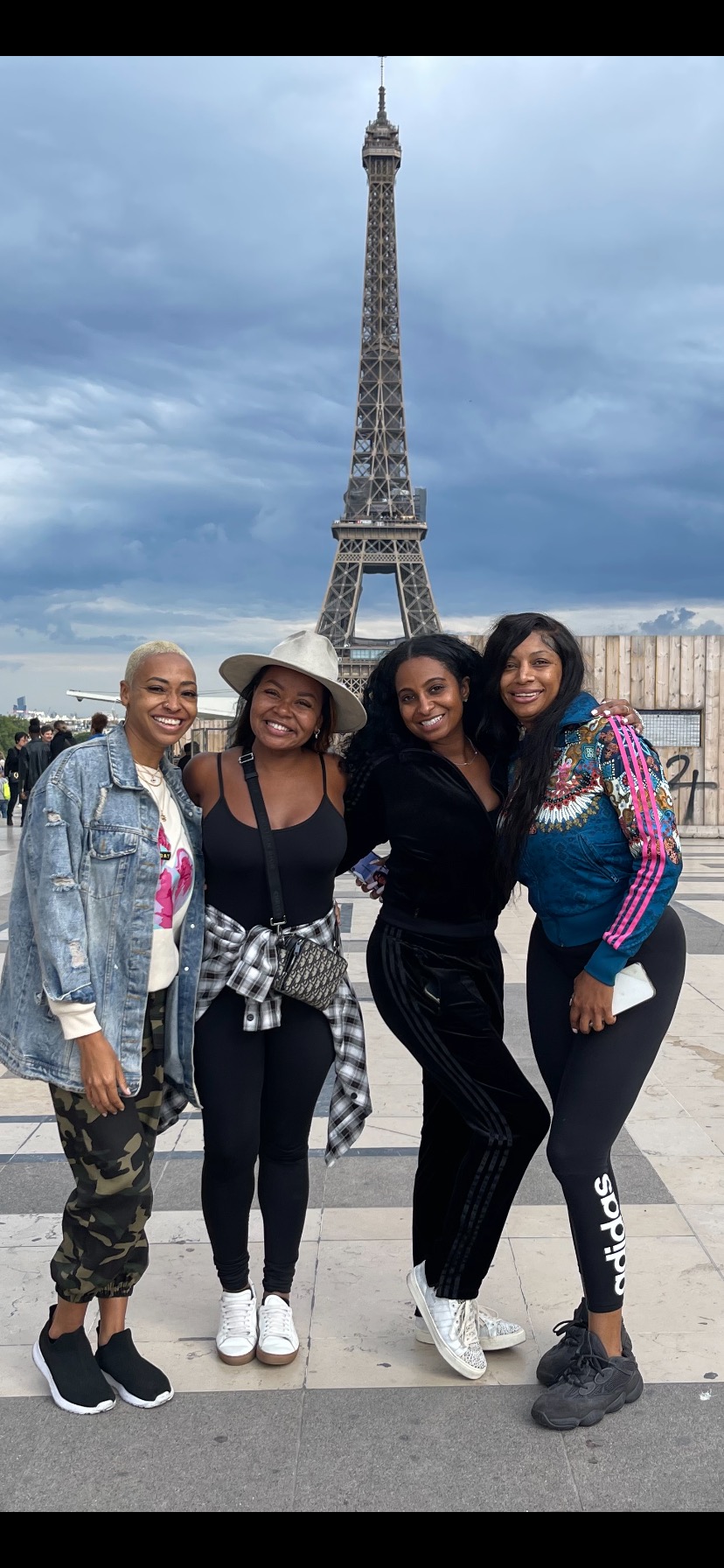 A group of four women poses joyfully in front of the Eiffel Tower