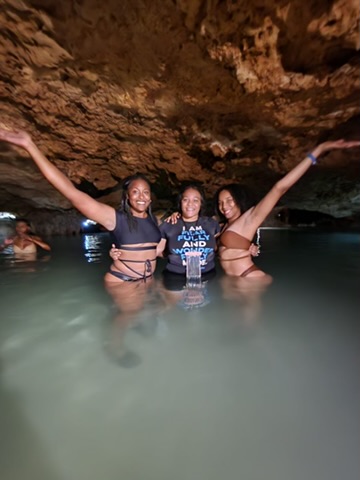 Three women wade in the water inside a cave